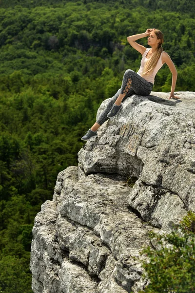 运动的女孩坐在山顶以山的看法与森林和山在背景上 夏季时间 — 图库照片