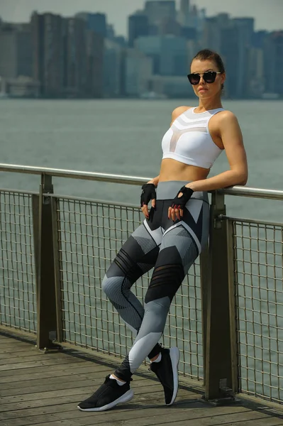 健身的年轻女子穿着时髦的运动装在码头上的阳光明媚的一天 — 图库照片