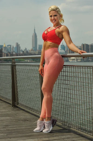 Genç, uygun ve sportif kadın iskelede poz. Fitness, spor, kentsel koşu ve sağlıklı yaşam konsepti.