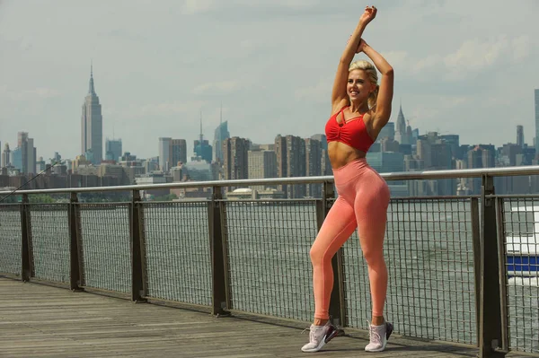 Seksi çekici genç kadın vücut iskelede güneşli gün zevk parlak spor giyim uygun.