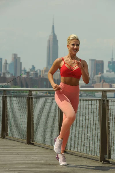 Güzel sarışın spor giyim bir sıcak yaz gününde koşu olarak yerleştirmek.