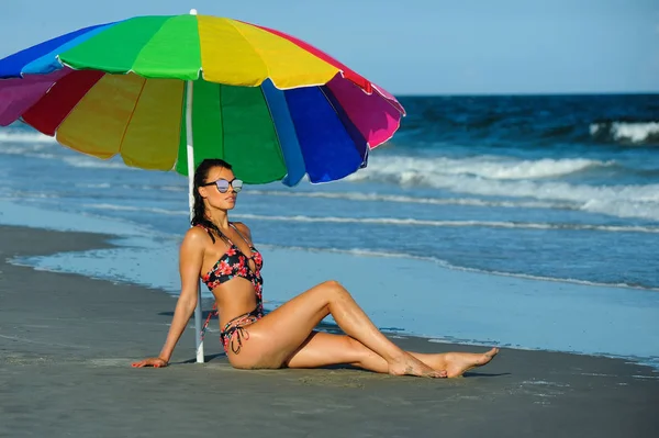穿着时髦泳装的性感黑发女郎坐在海边享受夏日时光 — 图库照片