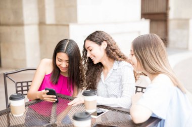 Güzel genç kızlar açık kafede kahve yaparken cep telefonunuzun