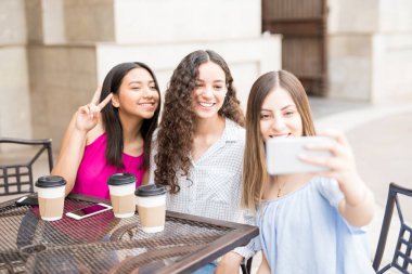 Kafe ve alma selfie cep telefonu ile dışarı asılı çekici genç kızlar.