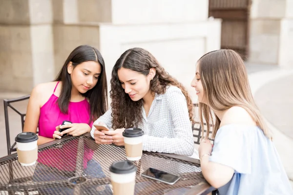 漂亮的年轻女孩在户外咖啡馆喝咖啡时使用手机 — 图库照片