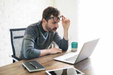 Latin yakışıklı masasında oturan ve yakından bakarak onun dizüstü bilgisayar