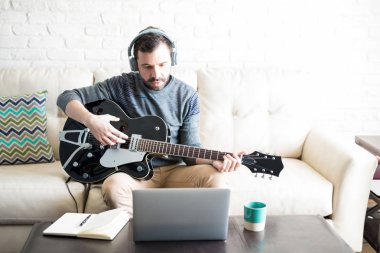 Müzik gitar çalmaya ve laptop seyir kulaklıklar ile yaratıcı latin delikanlı