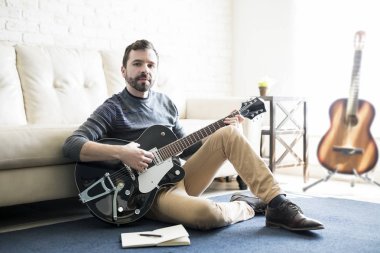Not defteri ile katta oturan ve gitar çalmak erkek şarkı yazarı portresi