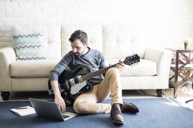 Gitar evde, yeni müzik kayıt İspanyol adam oynarken dizüstü kullanarak müzisyen
