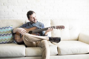 Çekici genç İspanyol adam evde bir gitar şarkıyı çalmaya