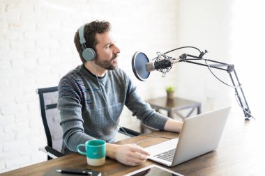 Kulaklık ve mikrofon, online radyo konuşurken laptop ile İspanyol Genç adam.