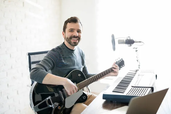 Lächelnder Junger Mann Sitzt Mit Gitarre Radio Und Macht Blickkontakt — Stockfoto