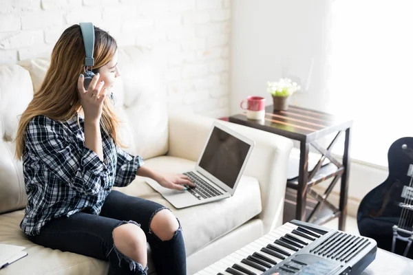 Młoda Kobieta Siedzi Kanapie Słuchawki Słuchanie Muzyki Laptopa Podczas Redagowania — Zdjęcie stockowe