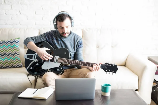 Креативний Молодий Латинський Чоловік Навушниками Грає Музику Гітарі Дивиться Ноутбук — стокове фото