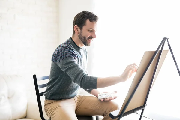 Sonriente Joven Latino Haciendo Algo Pintura Sobre Lienzo Sala Estar — Foto de Stock