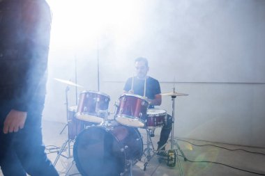 Rock band drummer in action on stage with lights and smoke clipart