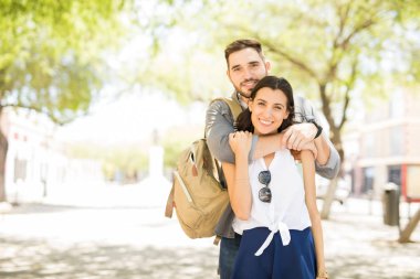 Güzel genç çift sarılma ve kameraya bakarak ve açık havada duran süre gülümseyen