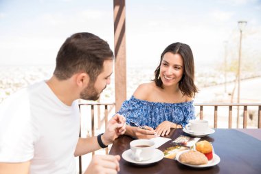 Genç kız açık havada sevgilisi ile masada otururken bir kağıt üzerine notlar birlikte yapma gülümseyen