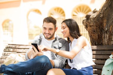 Bir bankta oturan bir akıllı telefon medya paylaşımı çift