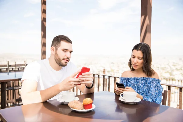 互联网成瘾的年轻夫妇使用智能手机在露台咖啡馆的早餐期间度假 — 图库照片