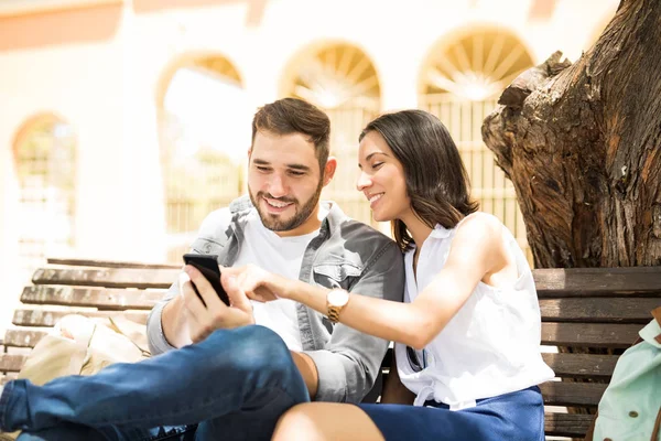 Bir bankta oturan bir akıllı telefon medya paylaşımı çift