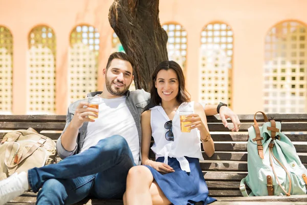 Bardak kırmızı şarap tutarak ve kameraya gülümseyen güzel zarif genç çift