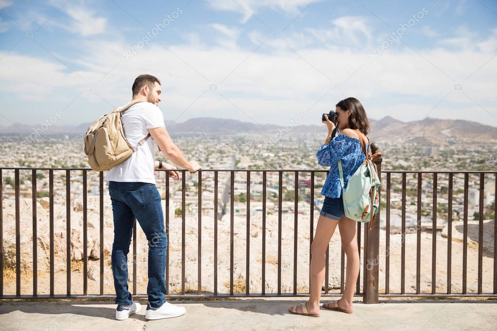 Full length of attractive young hispanic girl taking a picture with a digital camera