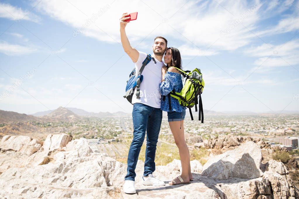 Adorable tourists woman and man in mountains make selfie uses mobile phone