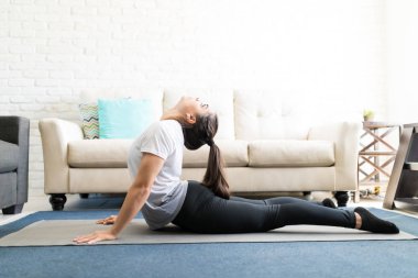 İspanyol kadın kobra poz evde oturma odasında pratik yan görünüm