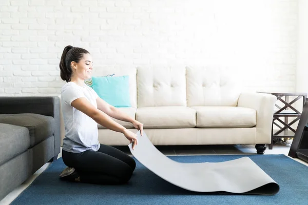 拉丁妇女放置瑜伽垫在起居室地板上锻炼 — 图库照片