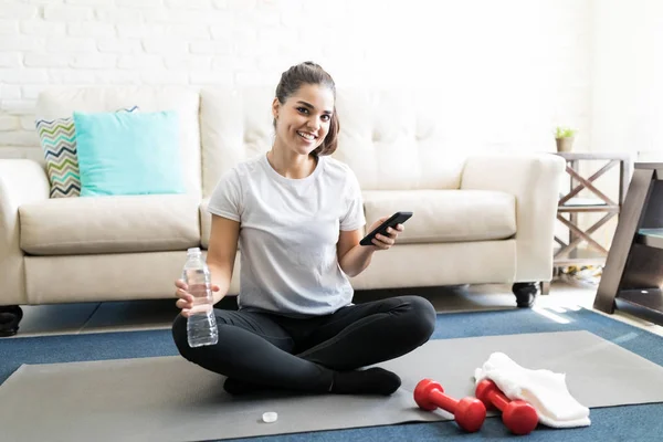 Jeune Femme Hispanique Assise Sur Tapis Exercice Avec Smartphone Bouteille — Photo