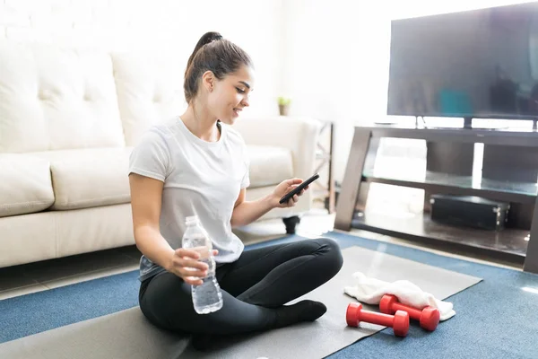 Young Hispanic Woman Sitting Exercise Mat Smartphone Water Bottle — Stock Photo, Image