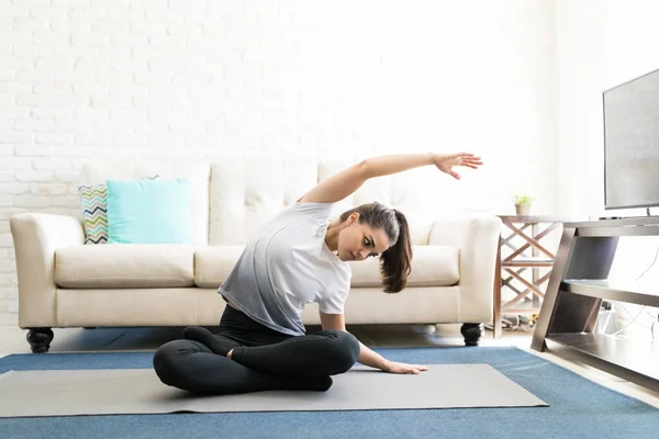 Junge Flexible Frau Sitzt Auf Yogamatte Und Beugt Sich Seitlich — Stockfoto