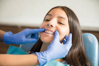 Eldivenler klinikte diş hekimi tarafından muayene ediliyor diş telleri ile genç kız