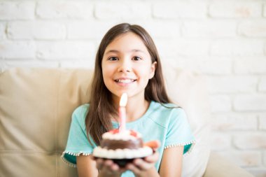 çikolatalı muffin bir yanan mum ile evde kanepede otururken tutan kız 