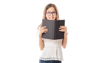 Beyaz gömlek ve gözlük tutan küçük sevimli kız portresi açık kitap beyaz arka plan 