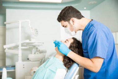 Erkek diş hekimine muayene bayan hasta ile diş kliniği araçlarında yan görünüm