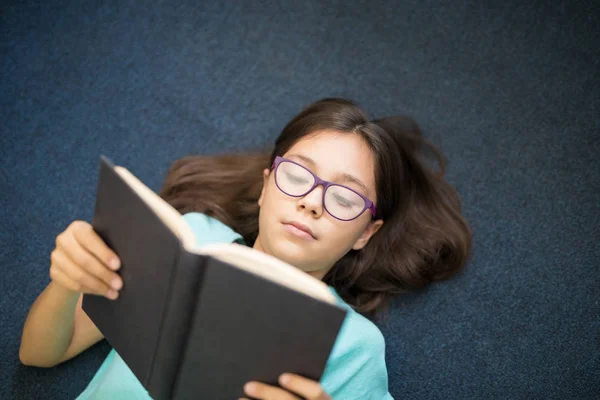 Menina Feliz Segurando Livro Aberto Enquanto Deitado Tapete Casa — Fotografia de Stock