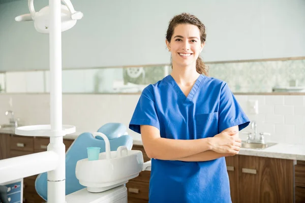 在临床上用交叉双臂站立的女牙医微笑的肖像 — 图库照片