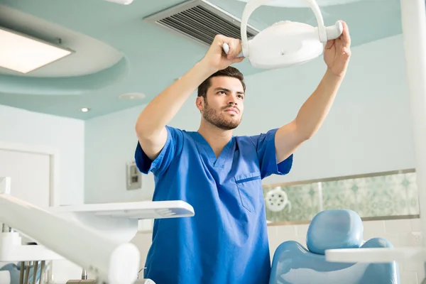 Dentista Masculino Adulto Medio Que Ajusta Equipo Iluminación Sobre Silla —  Fotos de Stock