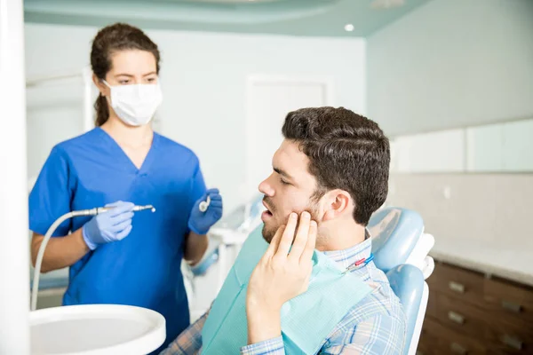 中年男子牙痛时 看牙医用工具在诊所 — 图库照片
