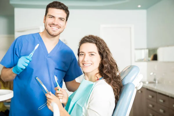 Retrato Dentista Sonriente Mujer Sosteniendo Cepillos Dientes Espejo Dental Clínica — Foto de Stock