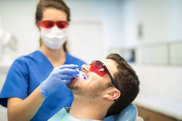 Dentista Revisando Hombre Adulto Medio Con Luz Ultravioleta Clínica Dental — Foto de Stock