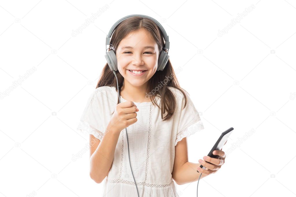 Fun young child enjoying rhythms in listening to music on headphones isolated on white background