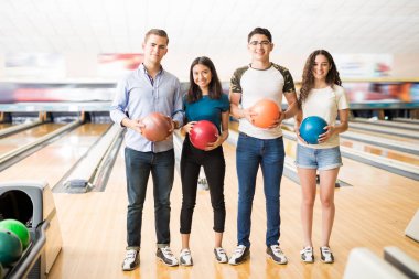 Bowling topları tutan ve birlikte kulüpte oynamak hazırlanıyor genç arkadaş grubu