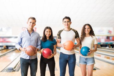 Bowling topları tutan ve birlikte kulüpte oynamak hazırlanıyor genç arkadaş grubu