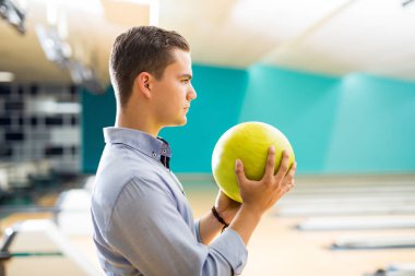 Kararlı genç çocuk kulübü sokakta, sarı bowling topu tutan yan görünüm 