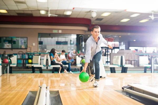 Özel genç çocuk kulübünde yeşil topu ile bowling oynamaya tam uzunlukta