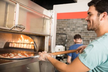 Yakın çekim portre raw koyarak giyen bir neşeli Şef eldiven pizza pizza dükkanı kabuğu kullanarak fırında hazırlanmış