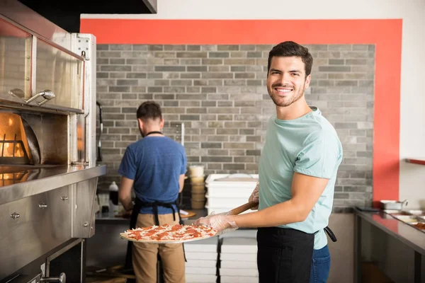 Cuoco Sorridente Grembiule Nero Che Mette Pizza Forno Con Buccia — Foto Stock